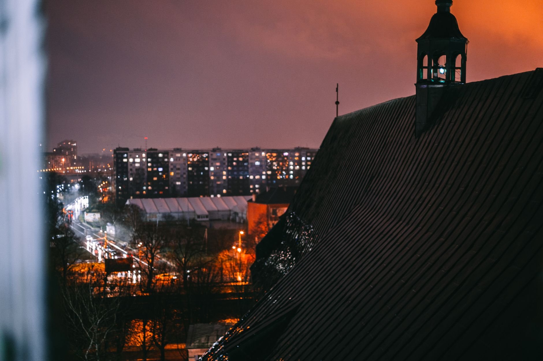 A city rooftop view showcasing illuminated streets and an urban skyline under a night sky.